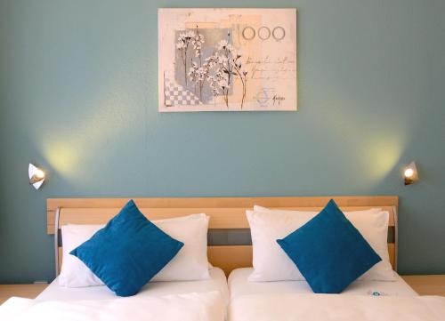 吕贝克黑伦霍夫酒店的一间卧室配有一张带两个蓝色枕头的床