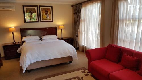 约翰内斯堡Jubilee Lodge Guest House的一间卧室配有一张床和一张红色的沙发