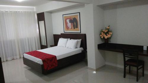 帕图斯迪米纳斯Center Patos Hotel的酒店客房配有一张床、一张书桌和一张四柱床