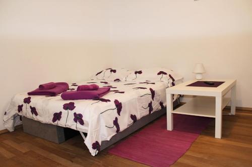 比奥格勒·纳·莫鲁Apartman Renata的一间卧室配有一张带紫色枕头的床和一张桌子