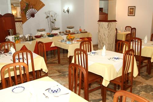 比利亚隆加Hotel Jr的餐厅设有白色的桌子和木椅