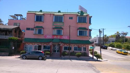 拉巴斯佩金酒店的一座粉红色的建筑,前面有一辆汽车