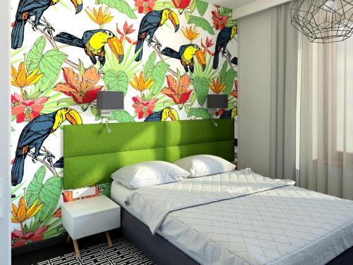 克拉科夫丽茵公寓式酒店的一间卧室配有绿色床头板和花卉壁纸