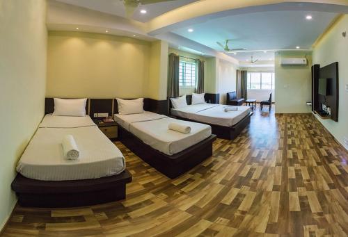 门格洛尔Hotel Bombay Residency--Bombay Lucky Restaurant的酒店客房设有两张床和电视。