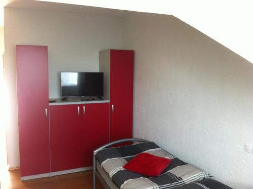 DunaszekcsőLandgasthof Hegau的一间卧室配有红色橱柜和一台平面电视。