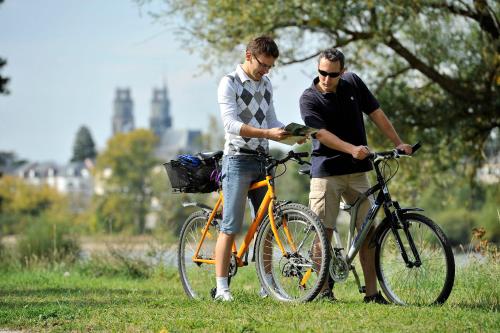 卢瓦尔河畔蒙路易Camping de Montlouis-sur-Loire的两个男人站在自行车旁,站在草地上
