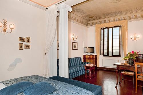 锡耶纳拉维佐宫酒店的一间卧室配有一张床、一张沙发和一张桌子