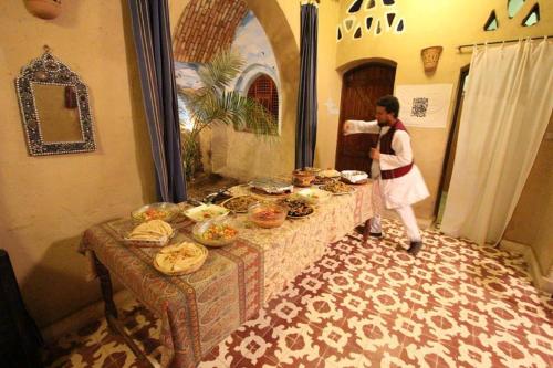 卢克索卢克索斯科普林旅馆的站在餐桌旁的一位妇女,那里有食物
