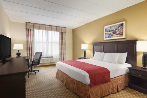 Mount Pleasant弗拉克维尔乡村套房酒店的酒店客房配有一张床、一张书桌和一台电视。