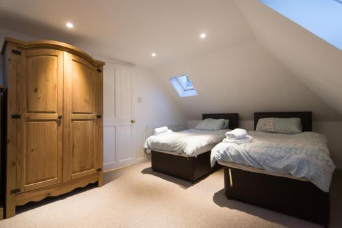 DouneBlair Drummond Holiday Home的阁楼卧室配有两张床和木制橱柜