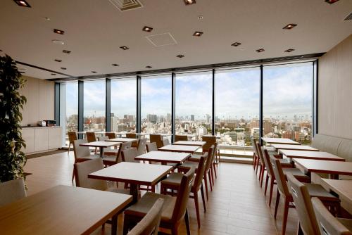 东京Hotel Crown Hills Ueno Premier的餐厅设有桌椅和大窗户。