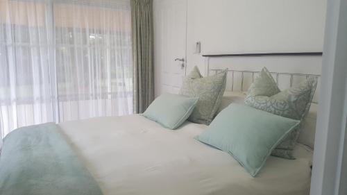 内尔斯普雷特Spring Acres Guesthouse的卧室配有带枕头的白色床和窗户。
