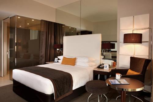 沙迦Centro Sharjah的酒店客房带一张大床和一把椅子
