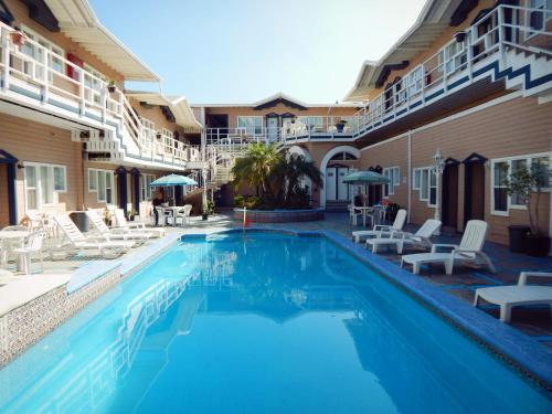 恩塞纳达港维拉丰塔纳酒店的一个带白色椅子的游泳池和一间酒店