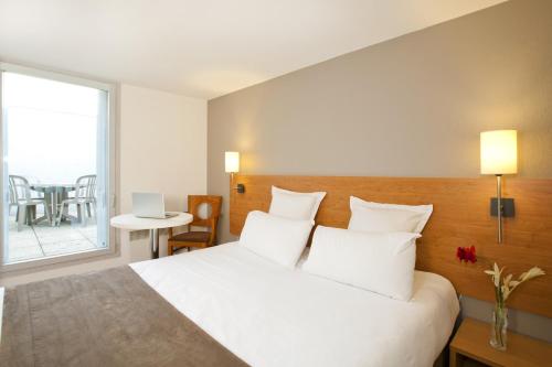 南特塞祖尔阿菲尔南特杜克布列塔尼酒店的卧室配有带白色枕头的床和窗户。