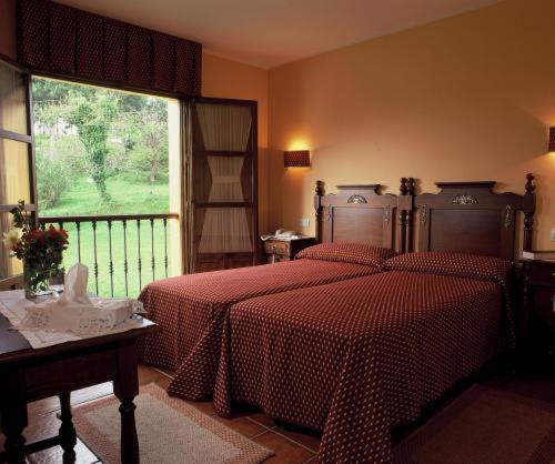 Camango卡莽古酒店的一间卧室设有两张床和大窗户