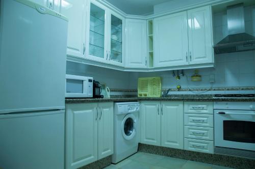 维拉·雷阿尔·德·桑托亚Our Little House的厨房配有白色橱柜、洗衣机和烘干机