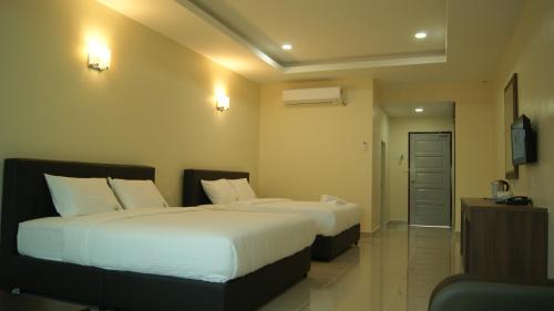 珍南海滩王谷度假酒店的酒店客房,配有两张带白色床单的床
