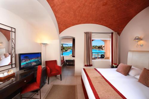 赫尔格达贾兹马卡迪绿洲度假酒店的一间卧室配有一张床和一台电视。