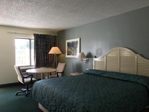 基西米Riviera Motel的酒店客房带一张床、一张桌子和椅子