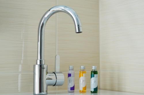 劳沙贝克酒店的浴室水槽设有水龙头和三瓶水。