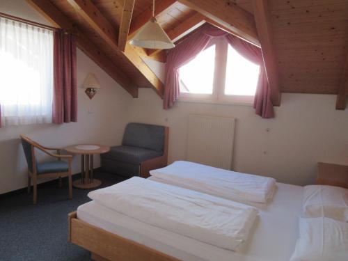 圣坎迪朵Appartements Johann Bachmann的一间卧室设有两张床、一把椅子和一个窗户。