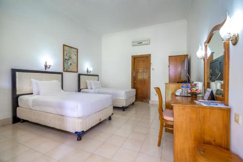 登巴萨巴厘岛英娜遗址酒店的酒店客房配有两张床、一张书桌和一张书桌。