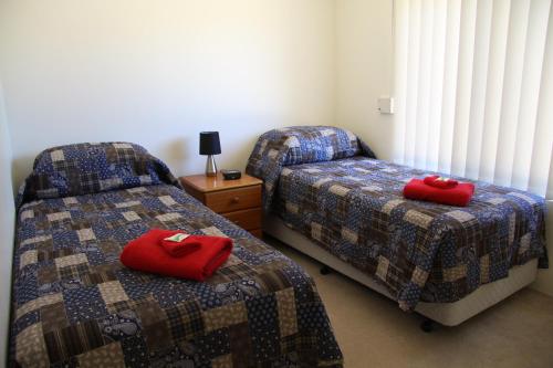 阿马代尔陡坡百富度假屋的宿舍间内的两张床,配有红色枕头