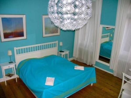 海德堡Hemingway`s Heidelberg Hostel的一间蓝色卧室,配有一张床和一个吊灯