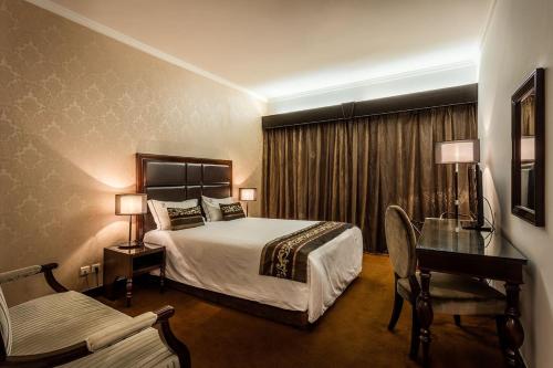 马普托大马普托贵宾酒店的配有一张床和一张书桌的酒店客房