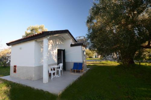 阿谢亚Villaggio Turistico Elea的一座白色的小建筑,在院子里放两把椅子