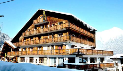 莫尔济讷康科尔德酒店的一座大建筑,设有雪地木制阳台