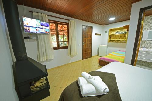 圣佩德罗塞拉Alta Colina Chalés的客房设有壁炉和带电视的床铺。
