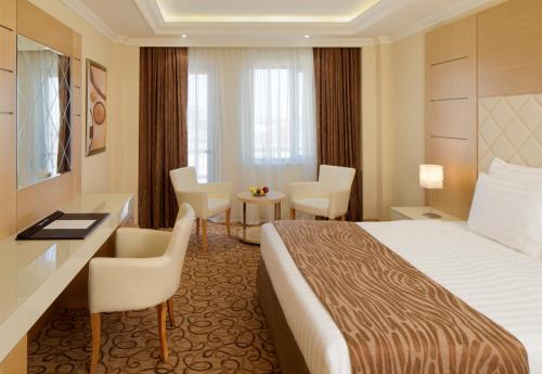 苏莱曼尼亚海克莱斯特酒店的酒店客房带一张床、一张桌子和椅子