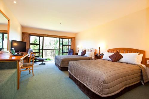特威泽尔Distinction Mackenzie Country Hotel的酒店客房配有两张床和一张书桌