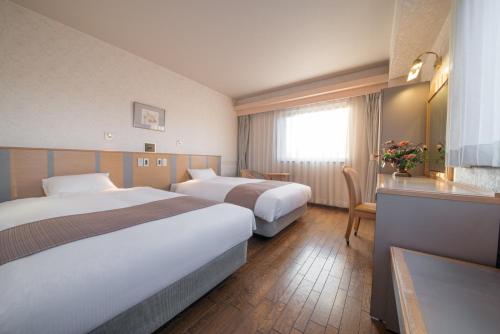 高山高山市四季酒店的酒店客房设有两张床和一张桌子。