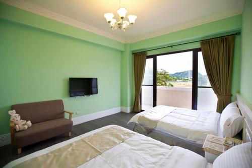 台东马约卡民宿的酒店客房设有两张床、一把椅子和电视。