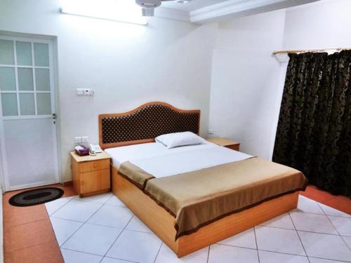 马斯喀特Sun City Hotel的一间卧室配有一张大床和木制床头板