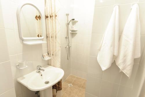 梁赞洛维奇体育酒店的白色的浴室设有水槽和淋浴。