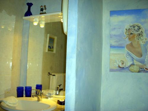Thorenc拉贝卡西亚酒店的一间带水槽的浴室和一幅女子绘画作品