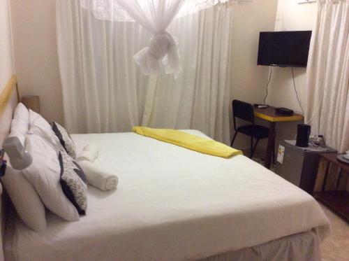 卡萨内Chiloto Guest House的卧室配有白色床,窗户上有一朵鲜花
