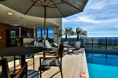 戈亚尼亚Quality Hotel Flamboyant的庭院配有桌椅和遮阳伞。