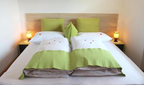 卡斯泰尔贝洛Villa Malus的一张带绿色和白色枕头的床以及两盏灯