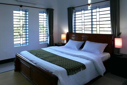 暹粒安欧之家旅馆的一间卧室设有一张大床和两个窗户