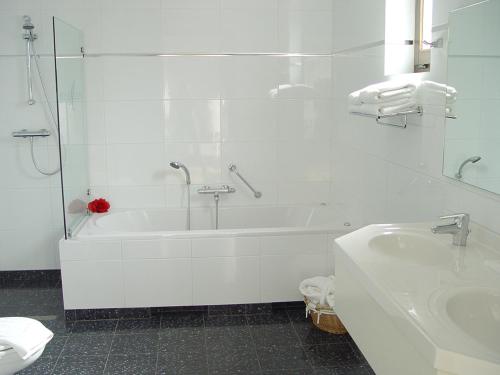 阿斯滕赫斯范赫斯登酒店的白色的浴室设有浴缸和水槽。