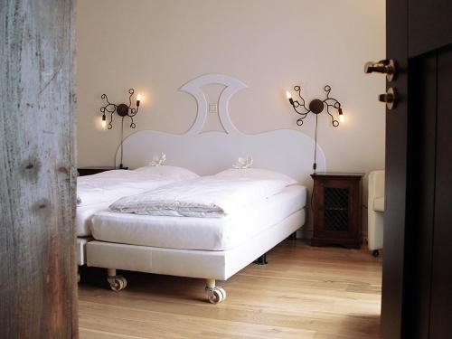 阿斯滕赫斯范赫斯登酒店的一间卧室配有两张带白色床单和灯具的床。