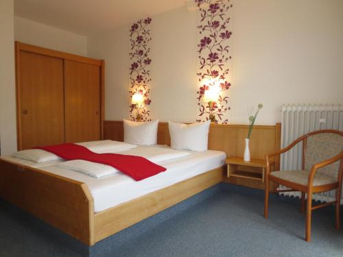 施泰因-埃伯恩堡地区巴特明斯特克朗酒店的一间卧室配有一张大床和一把椅子