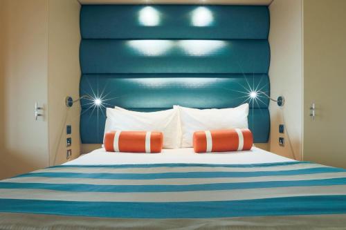 浦耳RNLI College的一张带蓝色床头板和两个橙色枕头的床