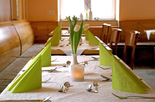 诺德林根Goldener Schlüssel mit Gästehaus Sina的一张长桌子,上面摆放着绿色椅子和鲜花
