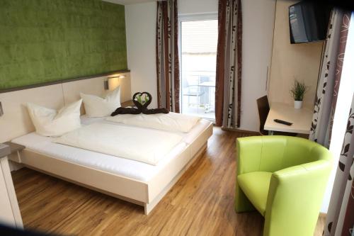 诺德林根Goldener Schlüssel mit Gästehaus Sina的卧室配有白色的床和绿色椅子